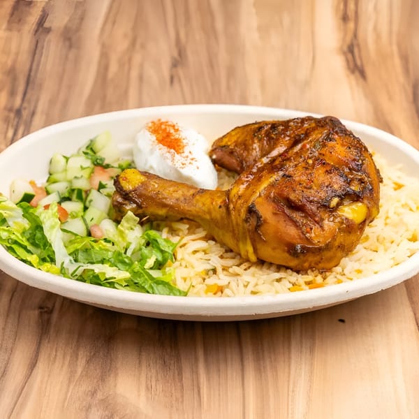 Two roasted chicken drumsticks with rice, a side salad, and a dollop of sour cream.